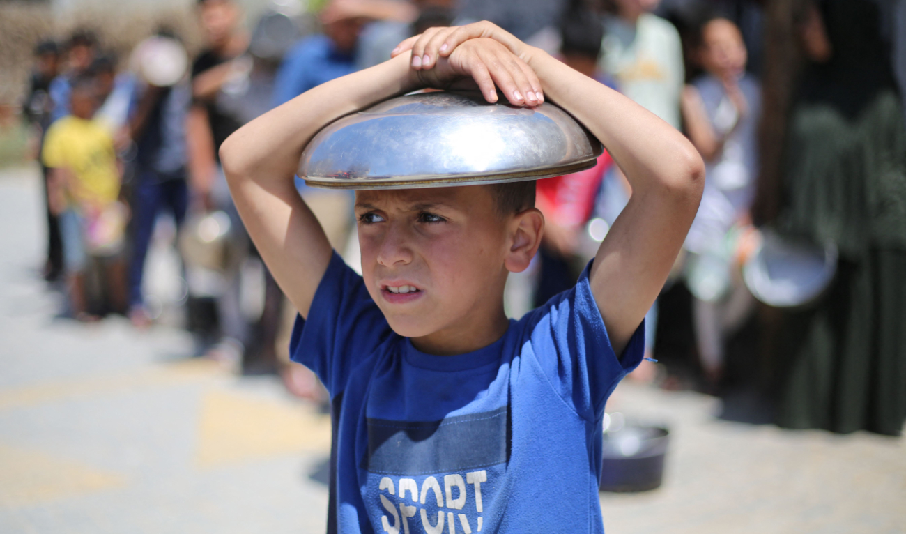 A Palestinian youth queues to receive a food portion from a charity kitchen in the Bureij refugee camp in the central Gaza Strip on Tuesday. (AFP)