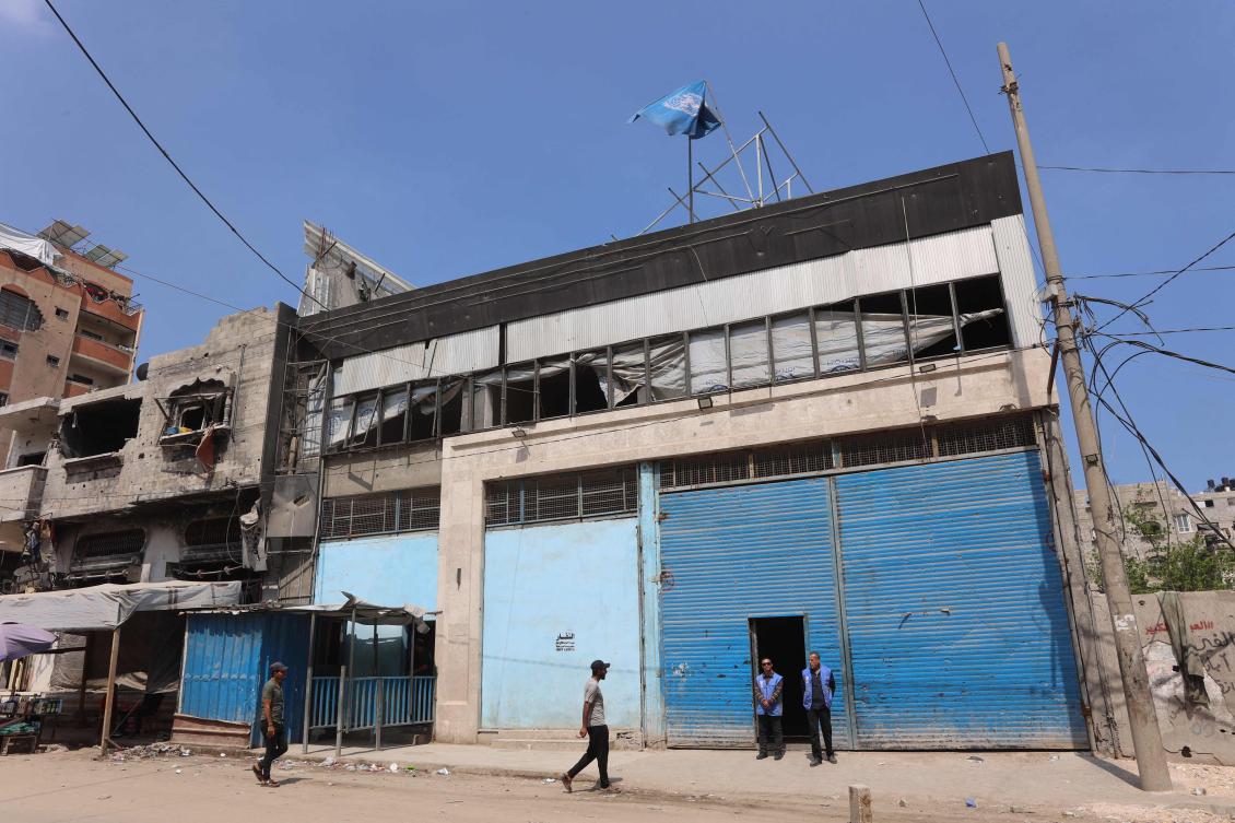 Members of staff stand at the entrance of a closed UNRWA aid distribution warehouse at al-Jalaa street in Gaza City on April 28, 2025. (Photo by Omar AL-QATTAA / AFP)