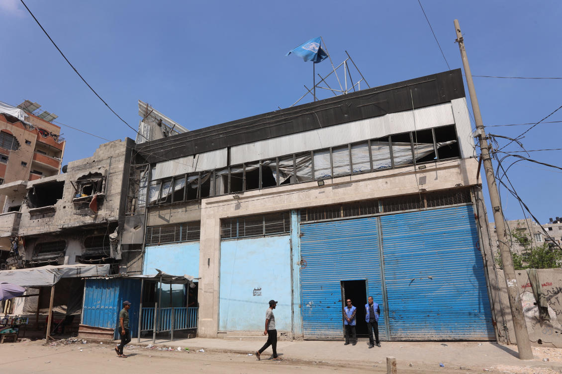 Members of staff stand at the entrance of a closed UNRWA aid distribution warehouse at al-Jalaa street in Gaza City. (File/AFP)