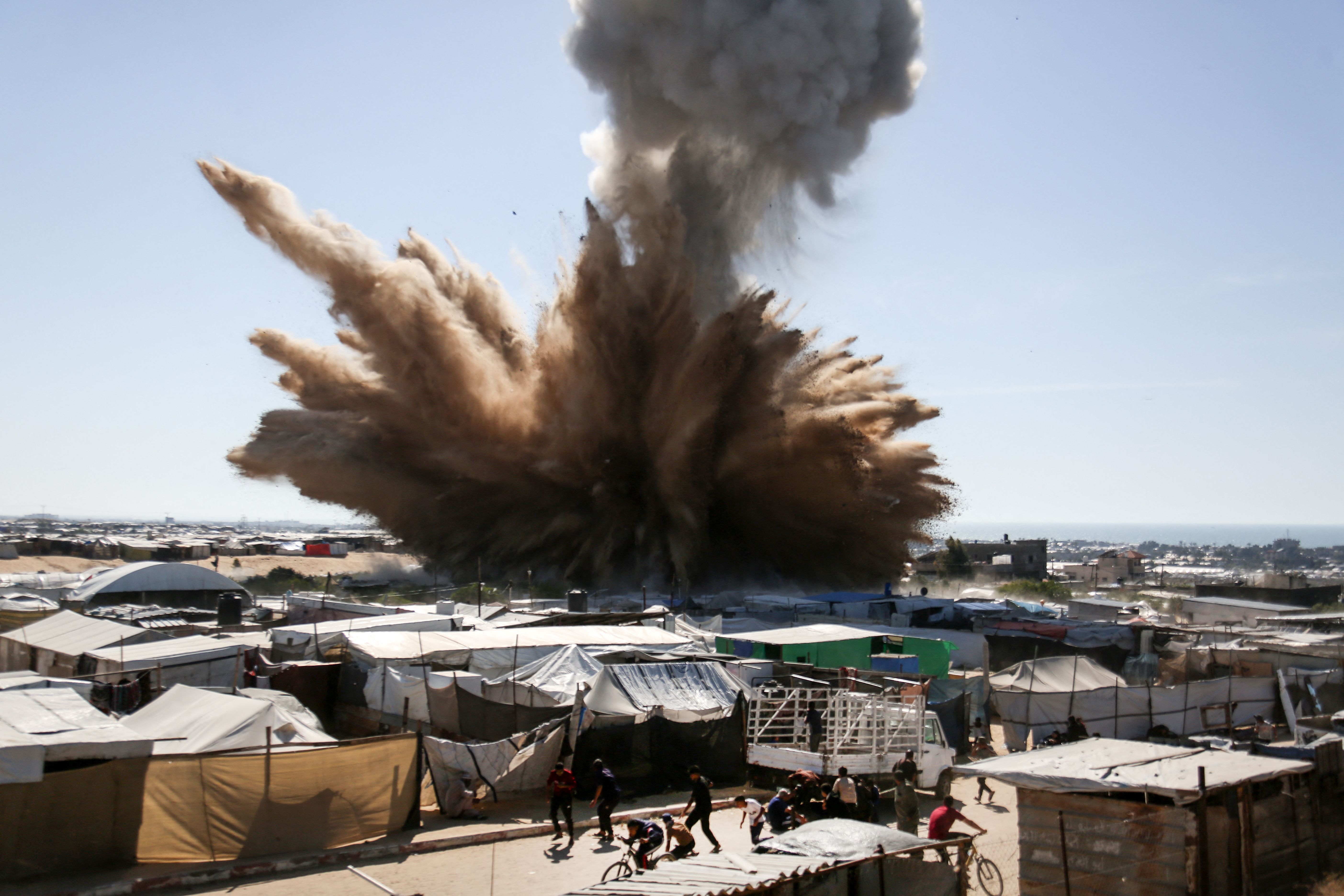 a plume of smoke rises above tents at a camp for displaced Palestinians in northern Khan Yunis. (AFP)