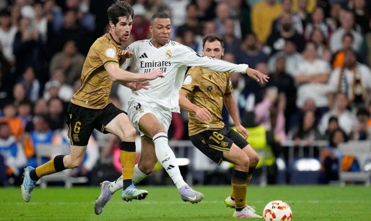 Real Madrid's Kylian Mbappe in action between Real Sociedad's Aritz Elustondo, left, and Jon Ander Olasagasti during the Spanish Copa del Rey semifinal second leg soccer match between Real Madrid and and Real Sociedad in Madrid, Spain Tuesday, April 1, 2025. (AP)