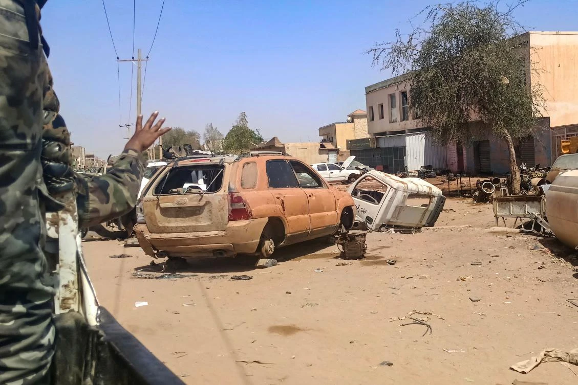 A Sudanese army soldier gestures from the back of a vehicle as it drives past damaged cars lying along a street in Khartoum on April 2, 2025. (AFP)