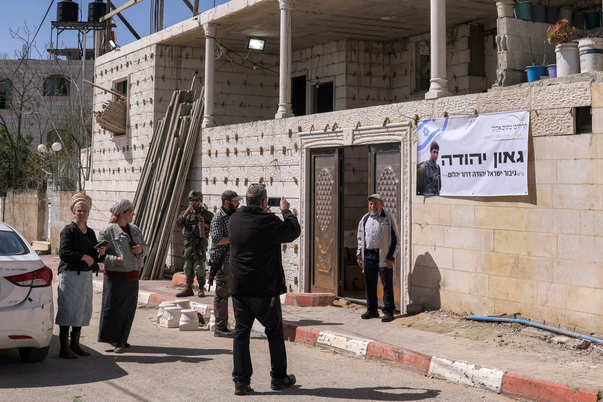 An Israeli settler takes a picture of another posing outside the Palestinian Ayoub Abdel-Basit al-Tamimi family house, which was allegedly taken over by Israeli settlers overnight, in Hebron. (AFP/File)