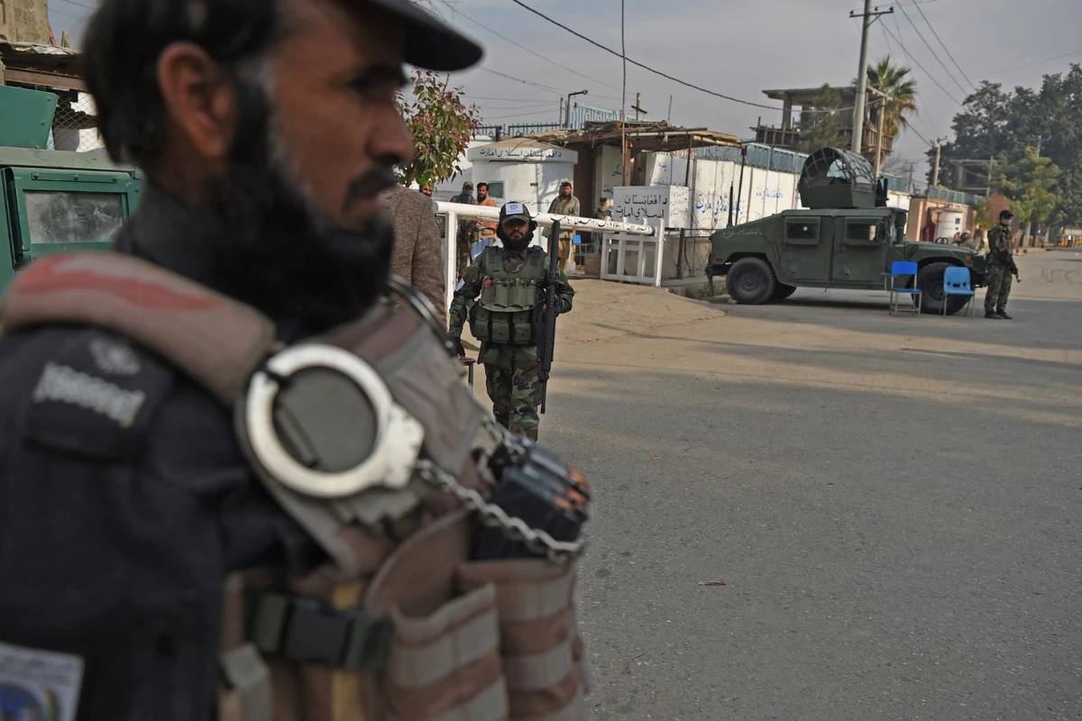 In this photograph taken on December 12, 2021, Taliban fighters stand guard in front of the office of the prisons administration in Jalalabad. (AFP)