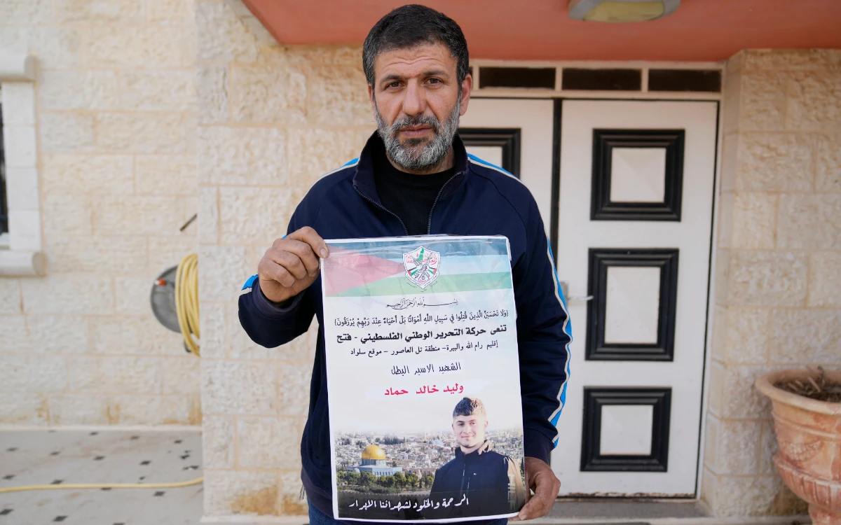 Khalid Ahmad holds a poster of his 17-year-old son, Waleed, who died in an Israeli prison. (AP)