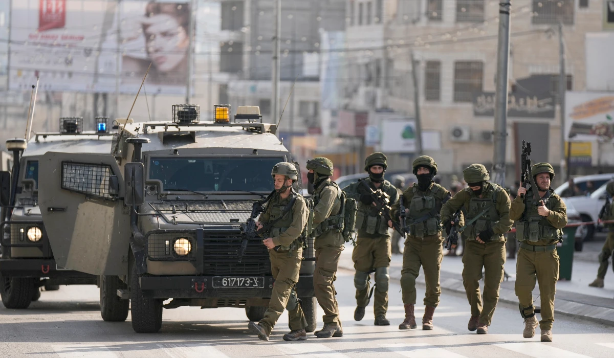 Israeli soldiers take up positions at the scene of a Palestinian shooting attack on an Israeli car at the Hawara checkpoint, near the West Bank city of Nablus, Sunday, Feb. 26, 2023. (AP)