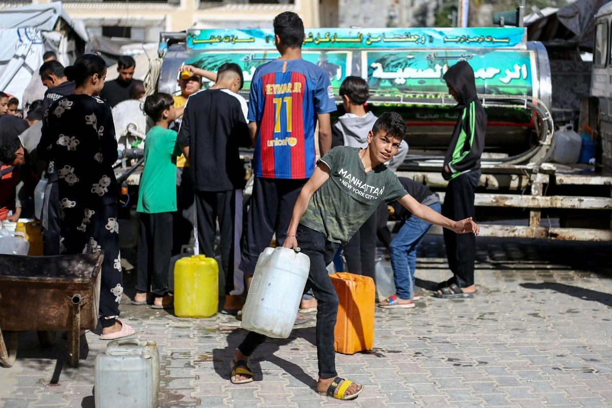 isplaced Palestinians line up to fill their containers with water at the Bureij refugee camp in the central Gaza Strip on April 10, 2025. (AFP)