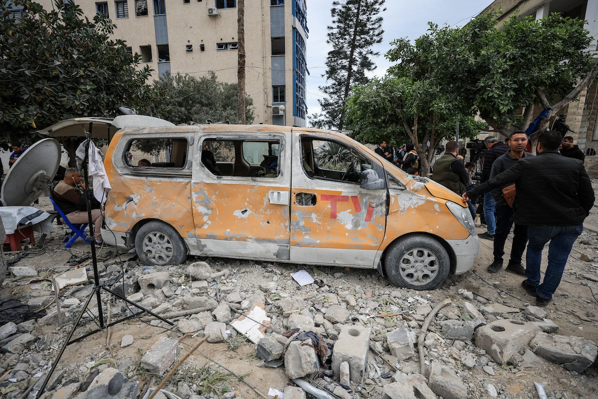 Palestinians stand near a damaged vehicle as they inspect the damage after two Israeli missiles hit a building inside Al-Ahli Arab Baptist Hospital. (Reuters)