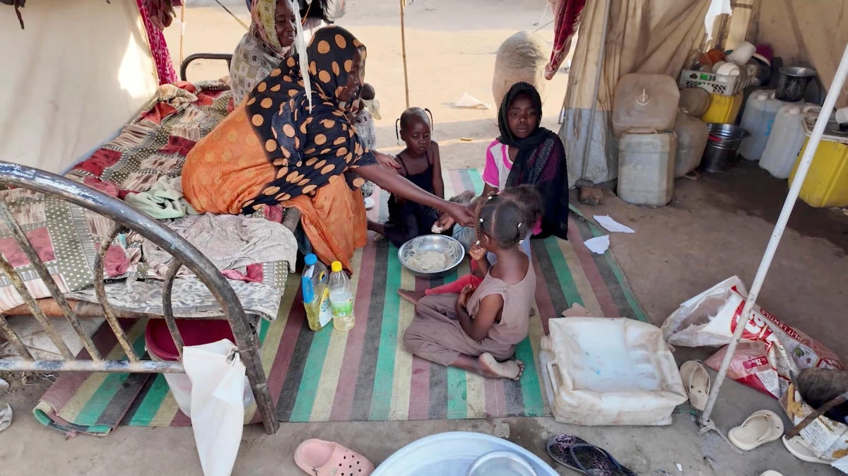 Awadiya Al-Day Ibrahim feeds her children with food prepared with supplies provided by World Food Programme, inside a tent, in Kassala, Sudan on March 19, 2025. (Reuters)