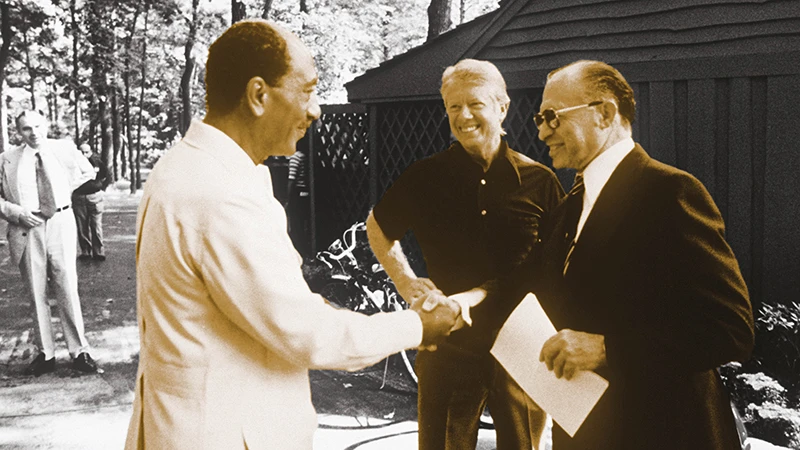 Anwar al-Sadat (L) shakes hands with Menachem Begin in the presence of US President Jimmy Carter. AFP