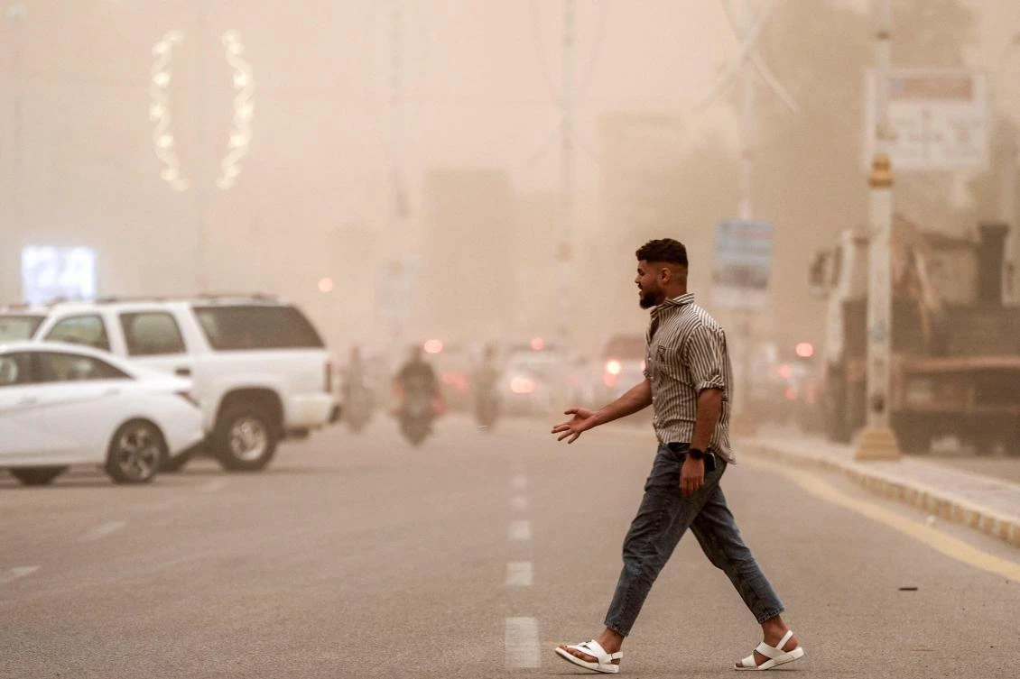 A man crosses a street through low visibility conditions as a massive dust storm advances on Nasiriyah in Iraq’s southern Dhi Qar province. (AFP)