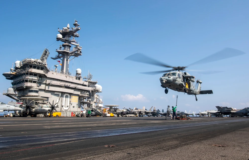 a military helicopter hovers over the uss carl Vinson aircraft carrier. (AP)