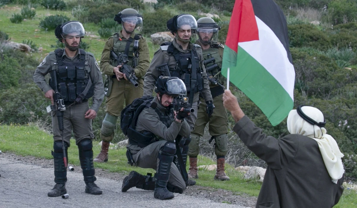 A man brandishes a Palestinian flag as members of the Israeli border police clash with Palestinians protesting Israeli settlements and a controversial US-brokered peace plan, in the Jordan Valley area of the occupied West Bank, on February 25, 2020. (AFP file photo)