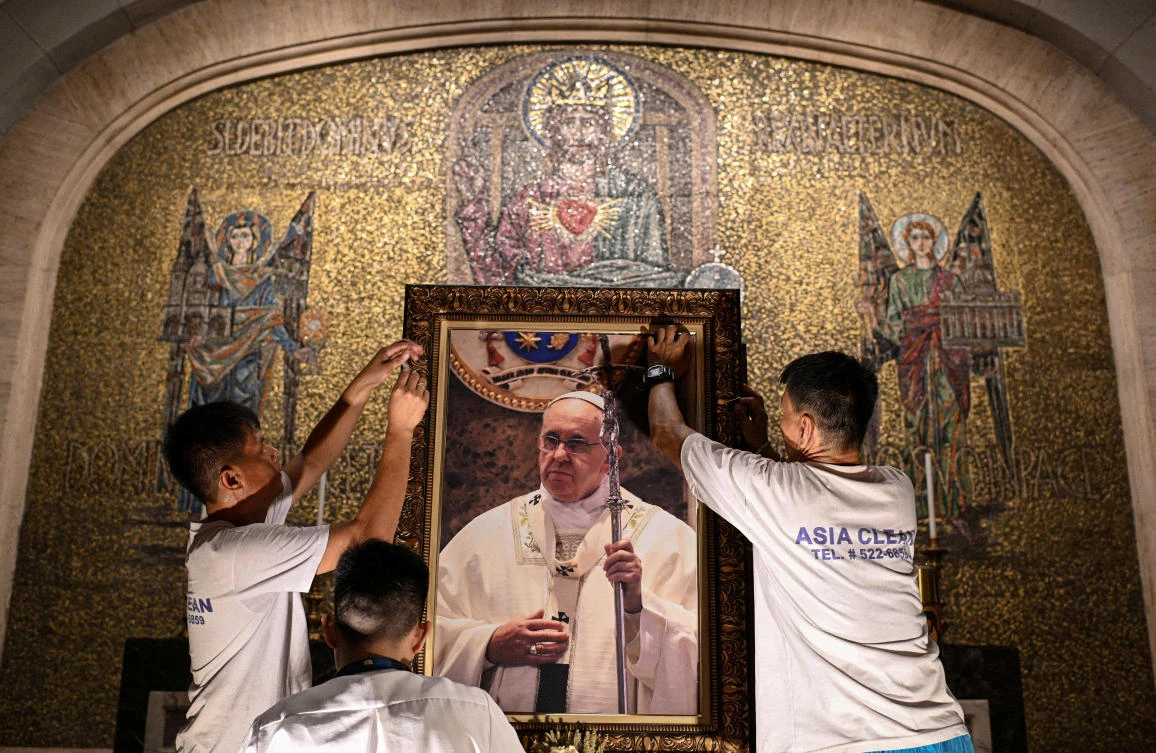 Church workers attach a picture of Pope Francis aftrer his death announced by the Vatican, at the Manila Cathedral, Philippines, Apr. 21, 2025. (Reuters)