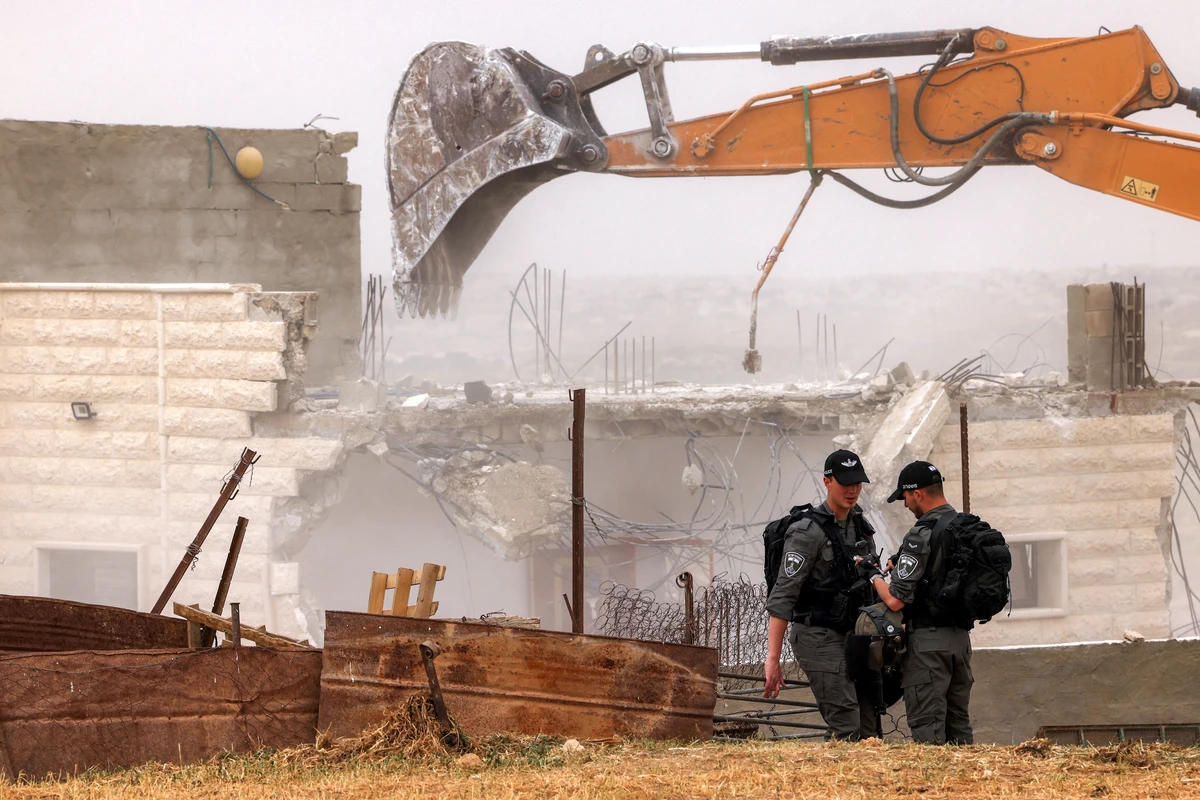 Israeli border guards stand by as Israeli excavators carry out the demolition of Palestinian buildings in the village of al-Samua, south of Hebron, Apr. 8, 2025. (AFP)