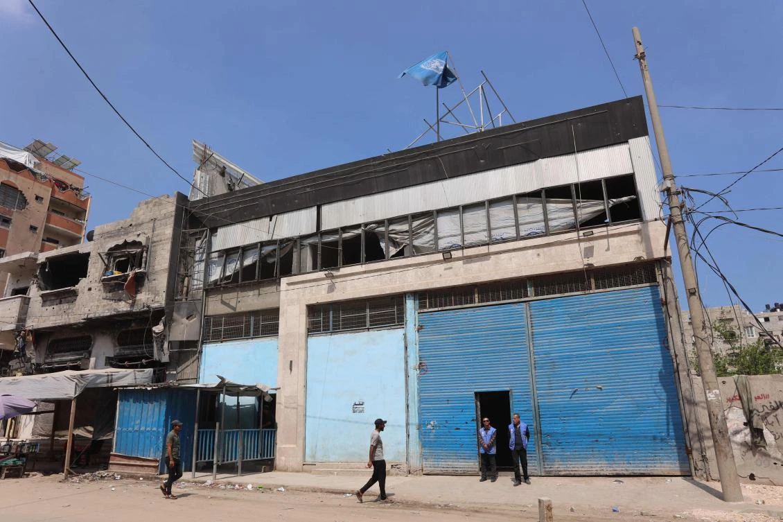 Members of staff stand at the entrance of a closed UNRWA aid distribution warehouse at al-Jalaa street in Gaza City on April 28, 2025. (Photo by Omar AL-QATTAA / AFP)