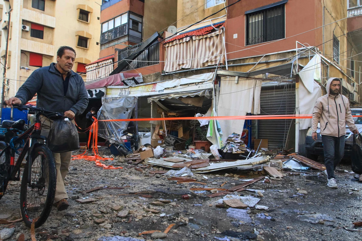 Local residents walk past debris in front of an apartment building following an Israeli strike in Sidon on April 4, 2025. (AFP)