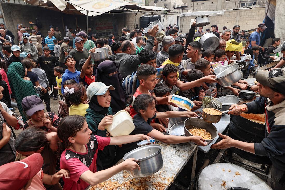 Palestinians gather to receive a hot meal at a food distribution centre in the Nuseirat camp for refugees. (File/AFP)