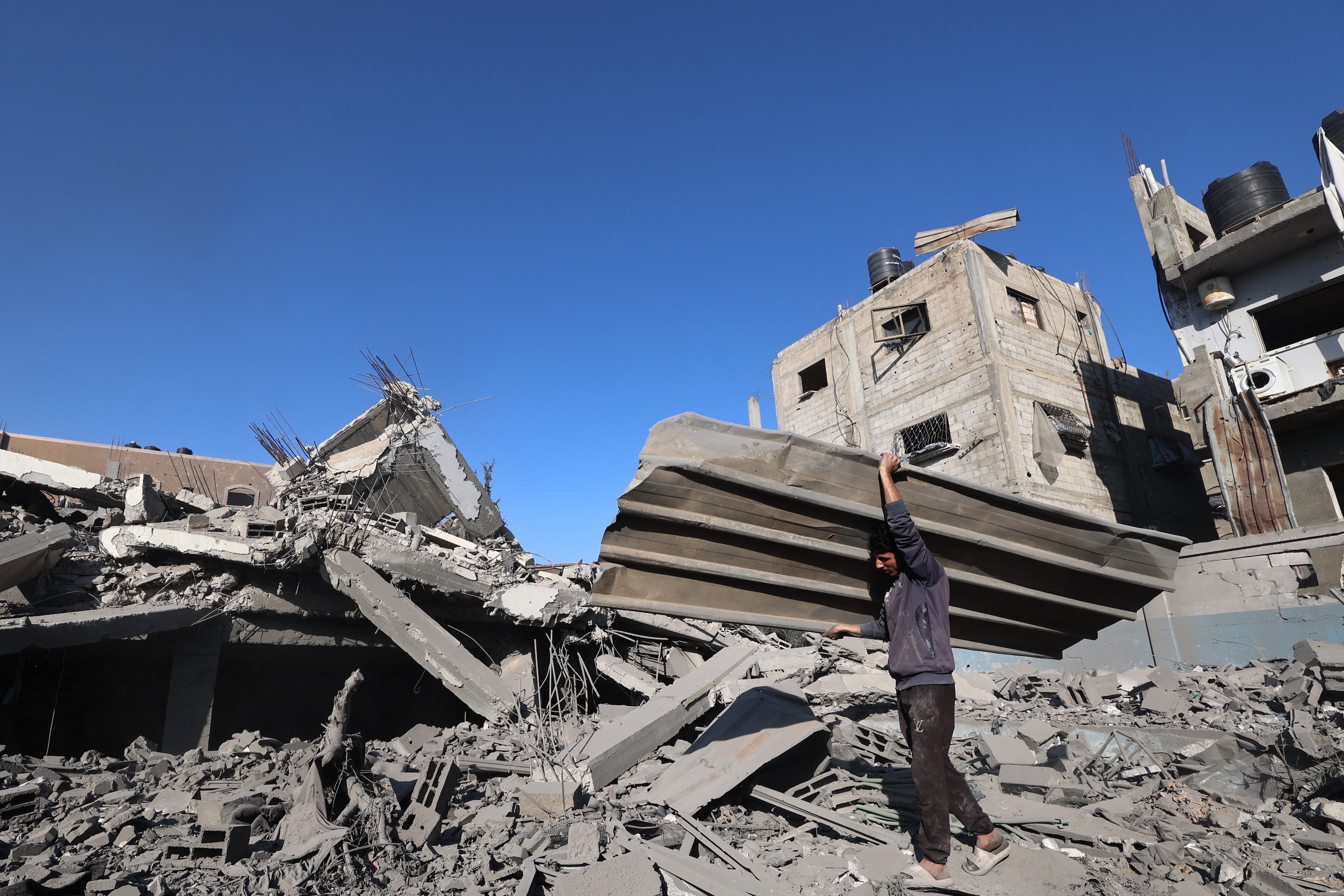 A Palestinian man carries debris as he clears rubble, following overnight Israeli strikes, at the Nuseirat refugee camp in the central Gaza Strip, Apr. 29, 2025. (AFP)