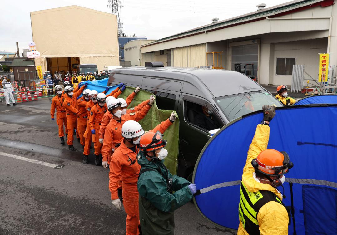 Firefighters guard a vehicle carrying the body believed to be that of a male truck driver, who was swallowed by a huge sinkhole three months ago, in Yashio City, Saitama Prefecture on May 2, 2025. (JIJI Press/AFP)