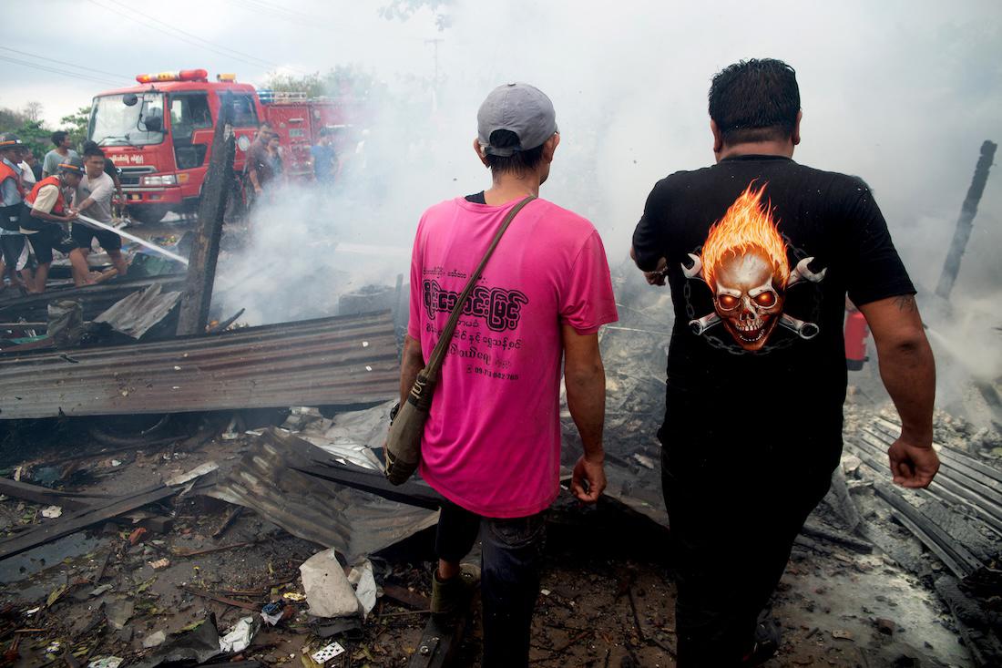 People extinguish a fire in a building that was destroyed in a bombardment carried out by Myanmar's military. (AFP)