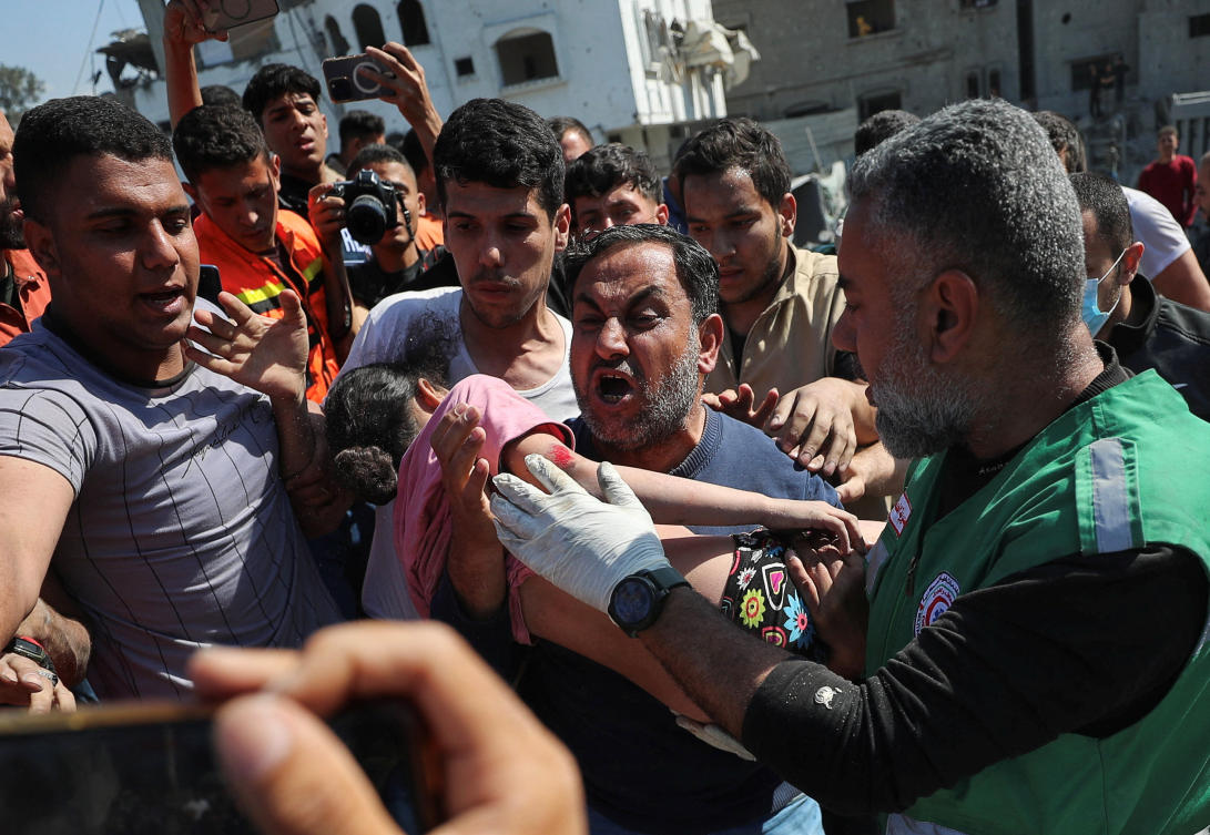 A man carries a girl, so she can receive medical attention, as Palestinians search for casualties at the site of an Israeli strike on a house in Jabalia, in the northern Gaza Strip on Friday. (Reuters)