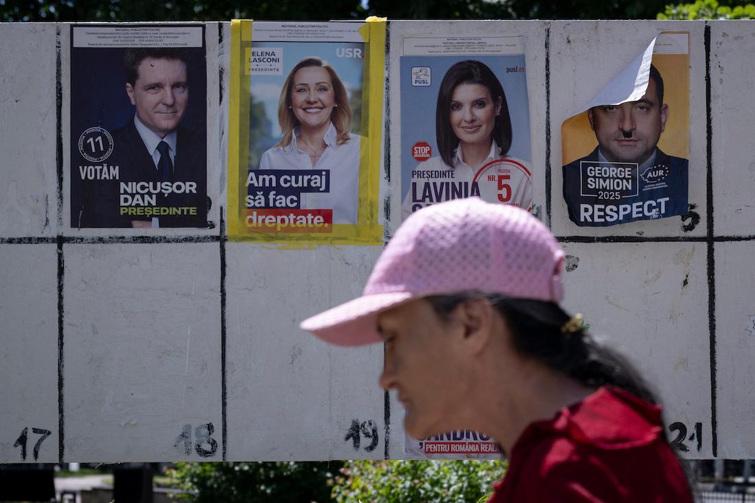 A woman walks past campaign posters on the eve of the first round of Romania's presidential election in Giurgiu. (File/AFP)