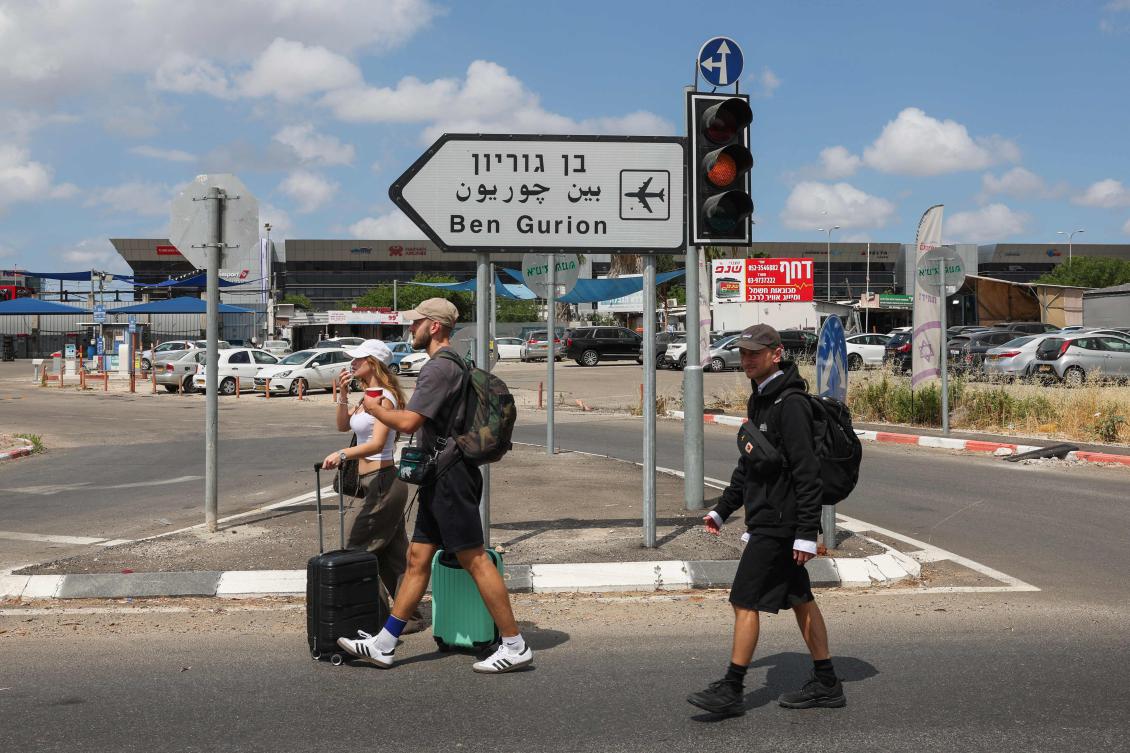 Travelers pull their luggage as they walk toward Ben Gurion airport after main road entrances to the facility were closed by Israeli Police, following air defense activation against missile launched from Yemen on May 4, 2025. (AFP)