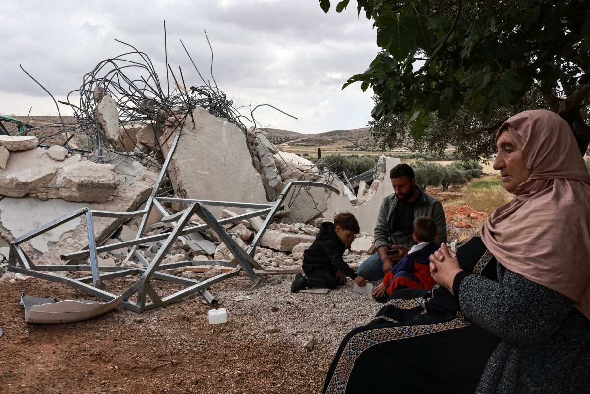 A Palestinian woman sits next to the rubble of her house, after it was demolished by Israeli forces, in the village of al-Mughayyer, north of Ramallah in the occupied West Bank. May 5, 2025. (AFP)