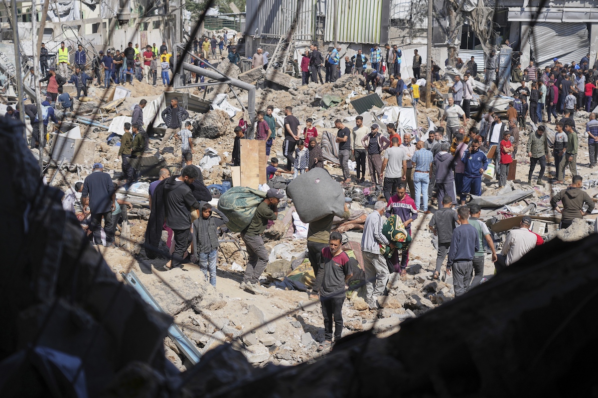 Palestinians collect belongings from a school in Gaza used as a shelter by displaced residents that was hit twice by Israeli army strikes on Tuesday, killing more than 25 people. (AP)