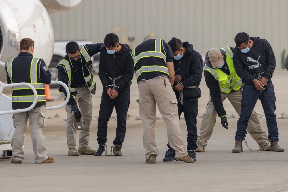 Security personnel pat down shackled migrants detained by ICE. (Getty Images/AFP)
