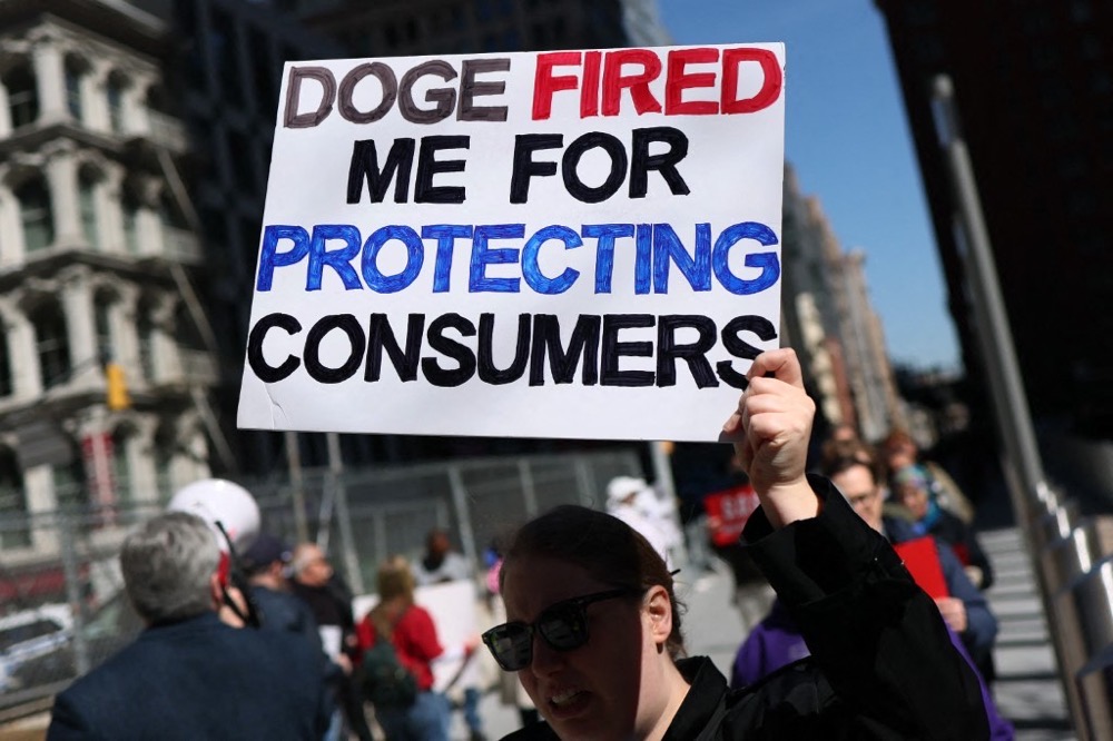 People hold signs as they hold an "informational picket" over DOGE's reductions to the federal workforce. (AFP/File)