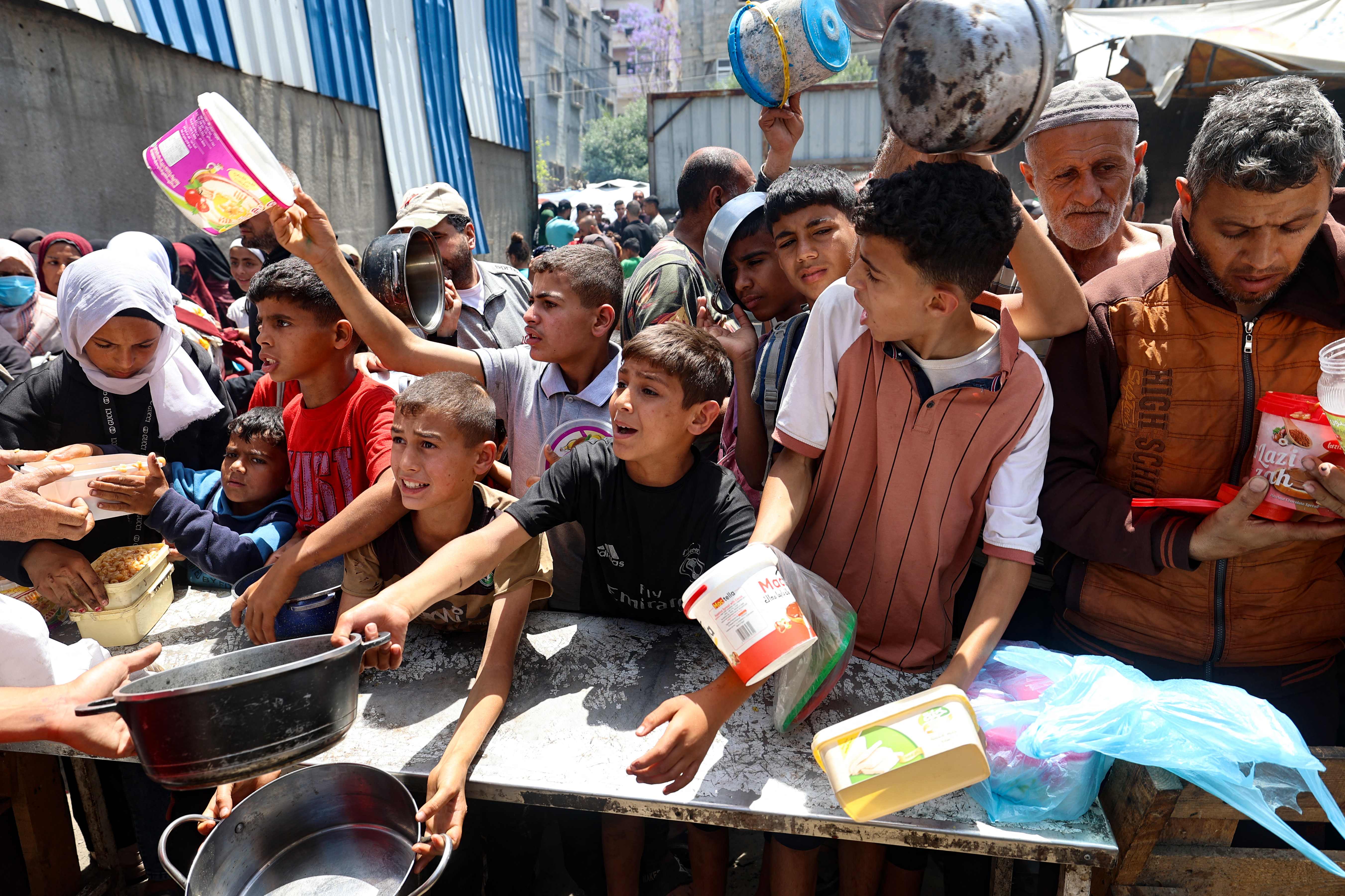 Palestinians jostle for position to get a hot meal, in front of a distribution point at the Nuseirat refugee camp in the central Gaza Strip on May 10, 2025. (AFP)