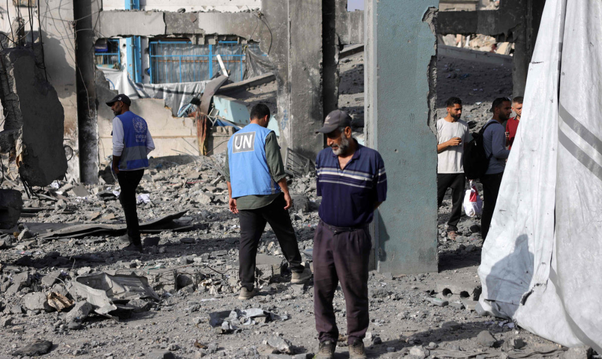 UN workers and displaced Palestinians stand amid the rubble of an UNRWA school-turned-shelter, heavily damaged in an overnight Israeli strike in Jabalia in the northern Gaza Strip on May 10, 2025. (AFP)