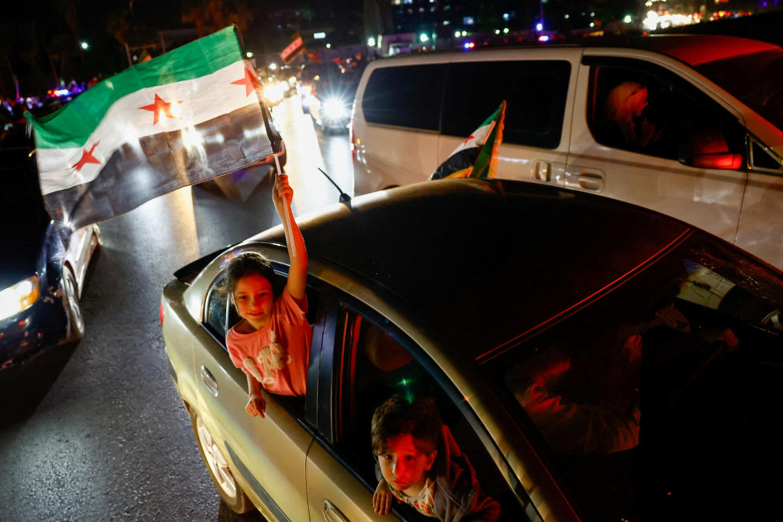 A girl holds a Syrian flag, as people in Damascus celebrate after US President Donald Trump said he would order the lifting of sanctions on Syria, May 13, 2025. (Reuters)