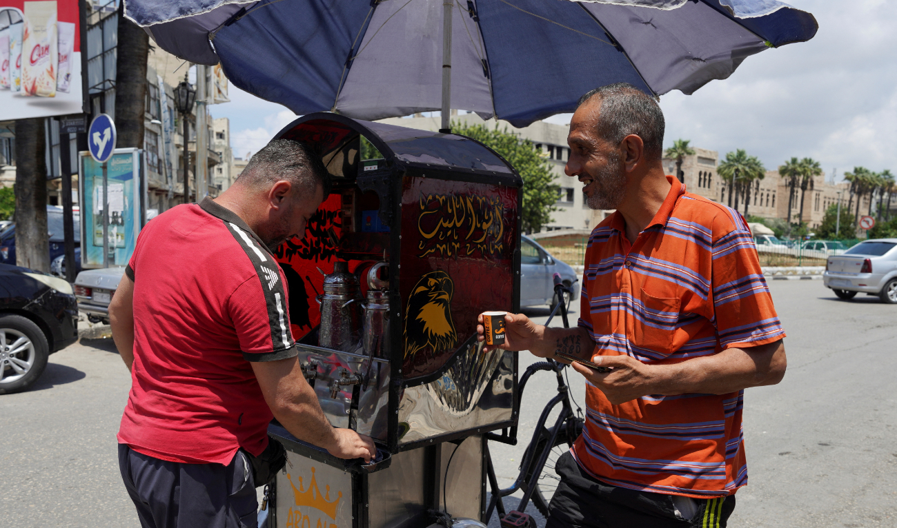 A man sells coffee on a street in Latakia, Syria. The gradual lifting of sanctions will likely boost the economy. (Reuters)