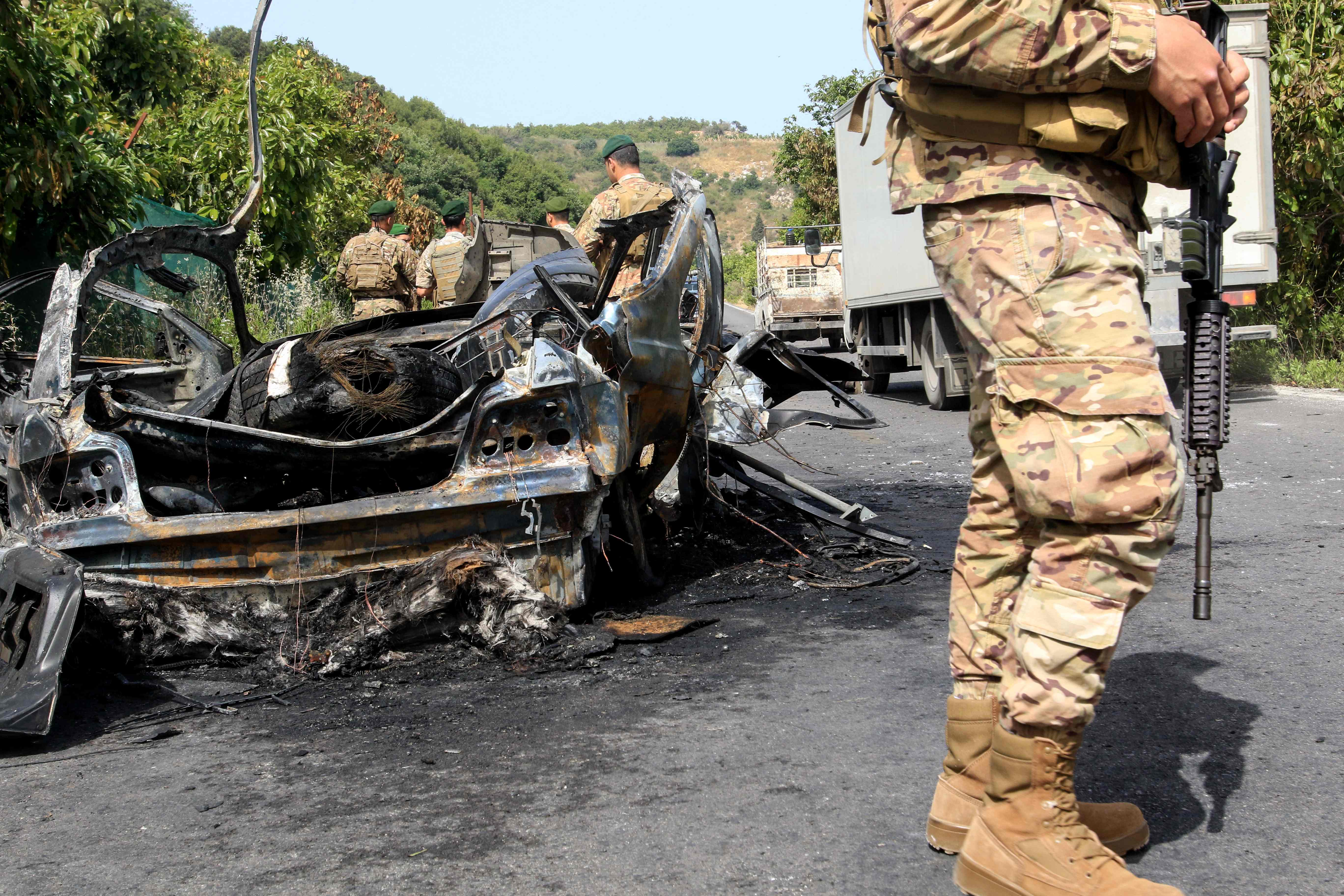 Lebanese army soldiers standing next to a destroyed car targeted by an Israeli drone strike in Abu al Aswad, Lebanon. (AFP)