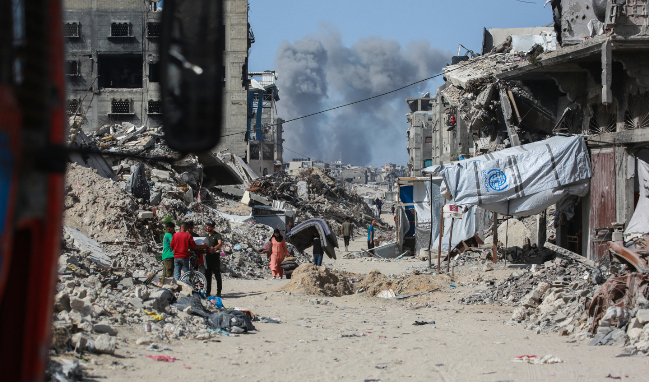 Smoke billows to the north as Palestinians move with their belogings through Jabalia while fleeing the northern Gaza Strip towards Gaza City on May 19, 2025. (AFP)