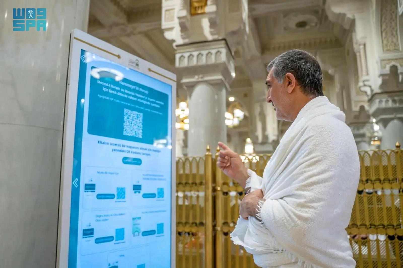 A pilgrim at the Grand Mosque in Makkah interacts with the AI-powered Manarat Al-Haramain Robot, which leverages advanced technologies to enhance the spiritual experiences of pilgrims. (SPA)