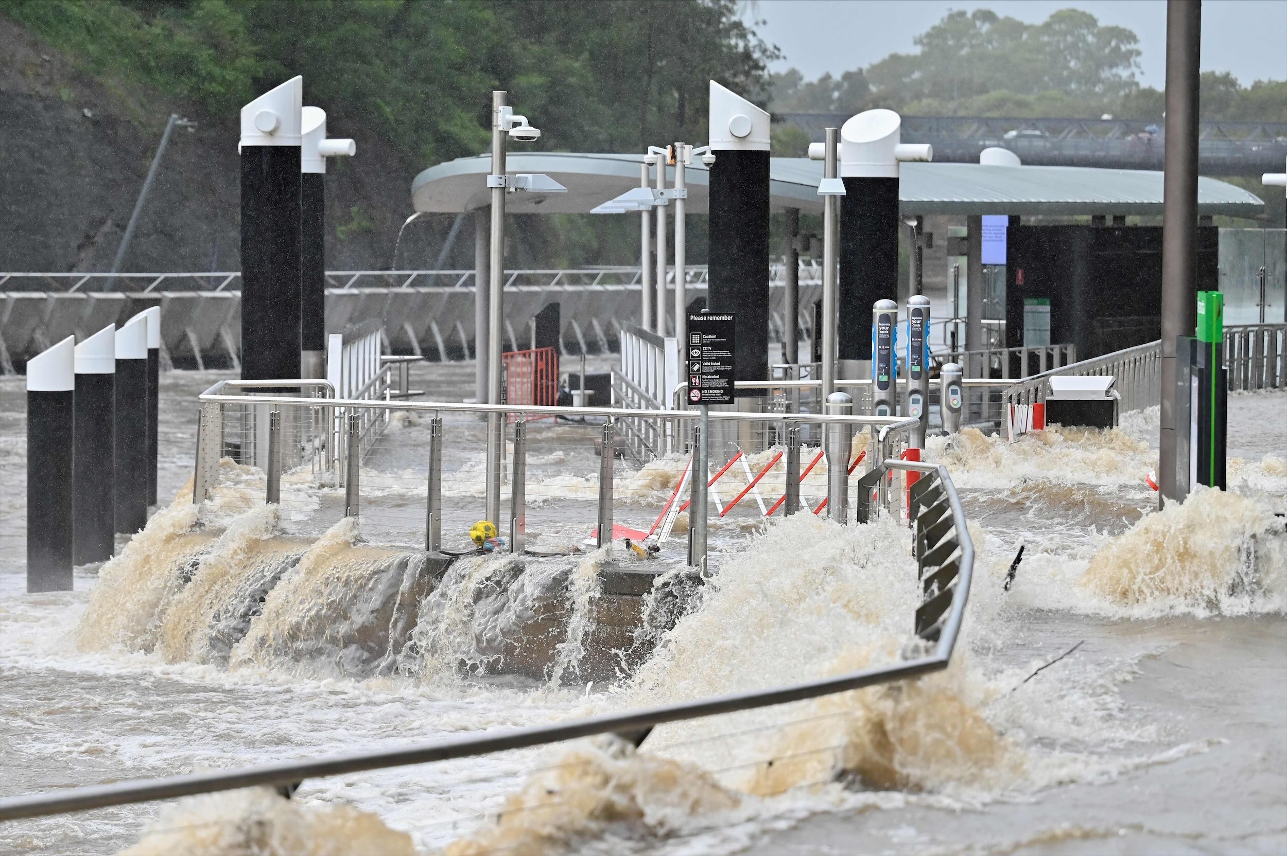 People clambered atop cars, houses and highway bridges before helicopters winched them away. (AFP)