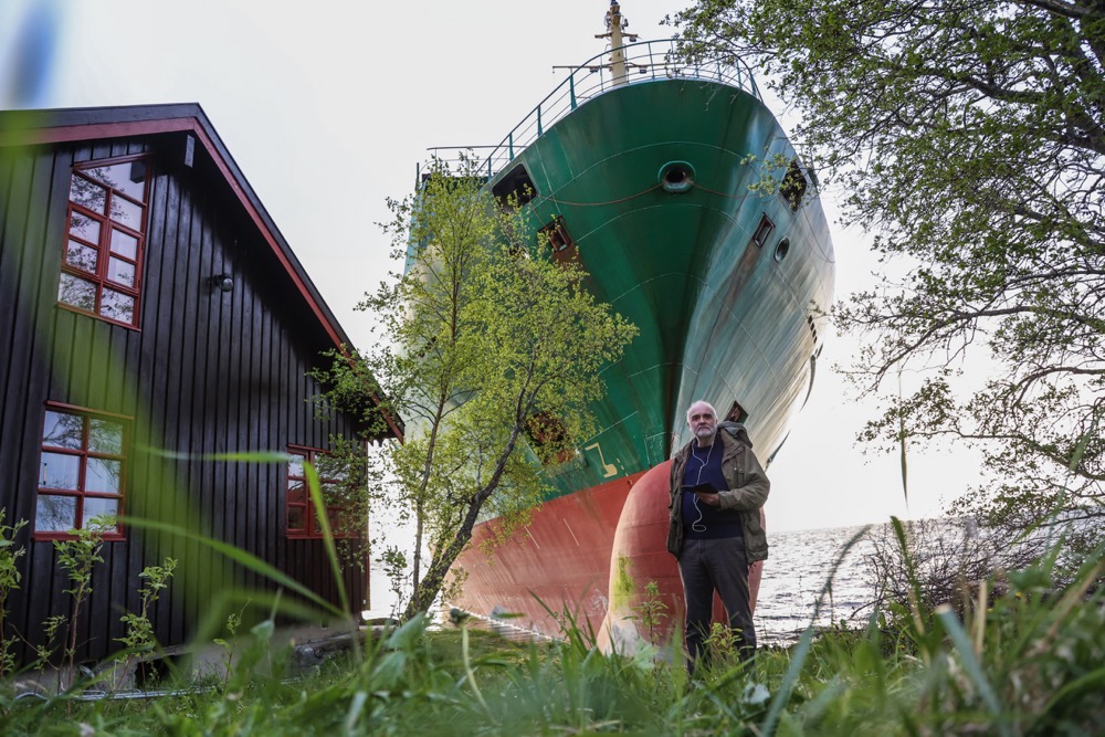 Johan Helberg stands next to his house, with the container ship NCL Salten in the background, after the 135-meter-long ship ran aground in the Trondheimsfjord, outside Byneset, in Trondheim, Norway. (AP)