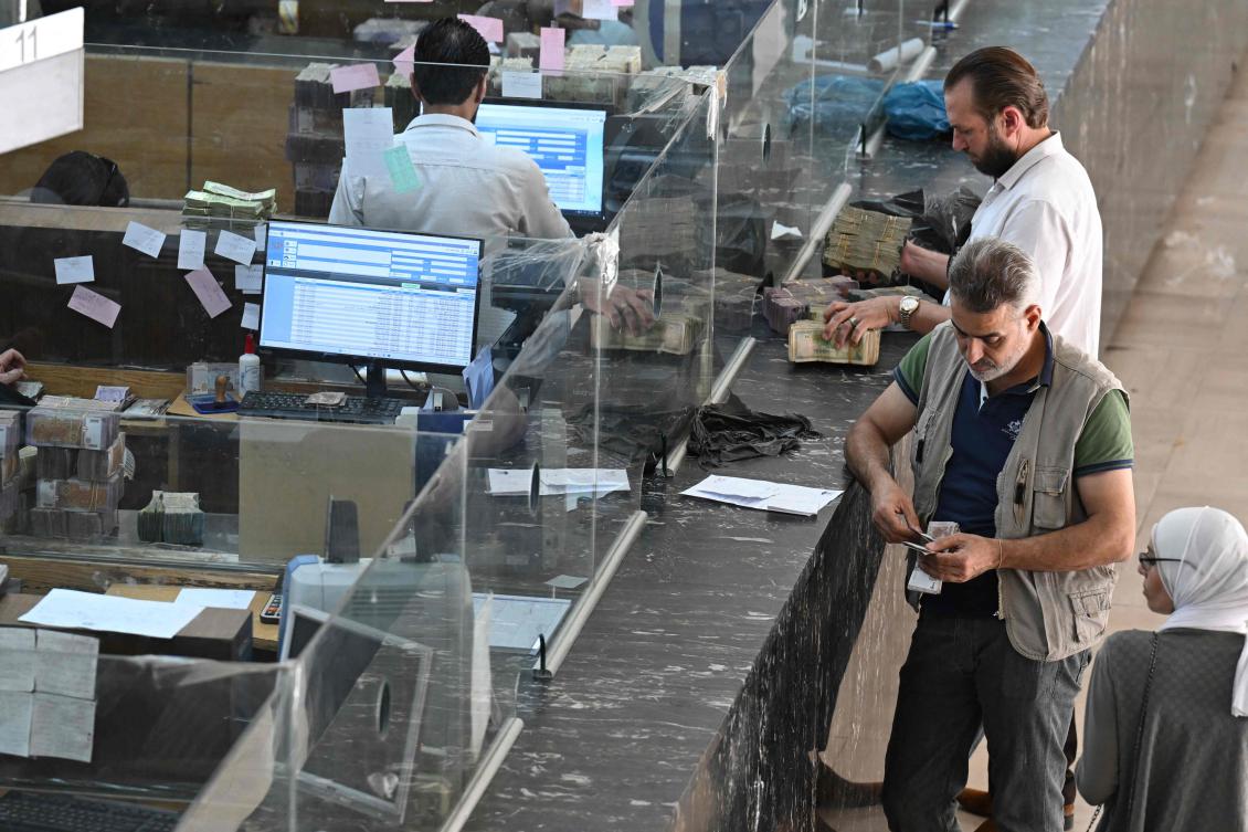 People wait at the central bank in Damascus on May 21. (AFP)