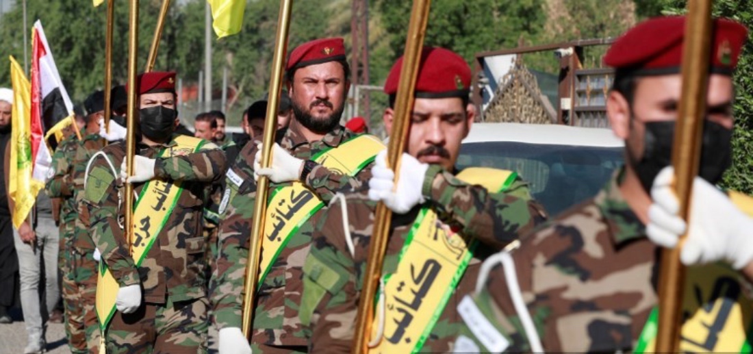 Fighters lift Kataib Hezbollah flags during a mourning march for five killed militants in Baghdad, Iraq. (AFP)