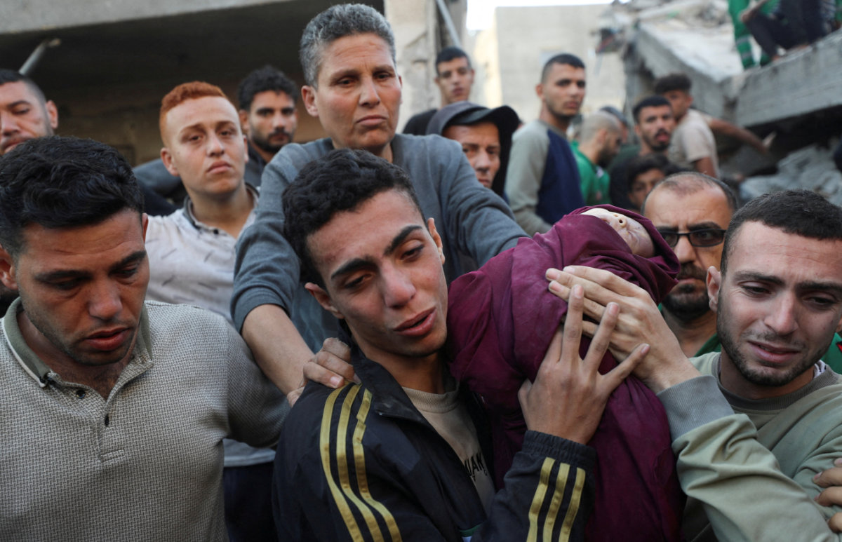 Palestinians carry an infant at the site of an Israeli strike on a house in Jabalia, northern Gaza Strip, on May 23, 2025. (REUTERS)