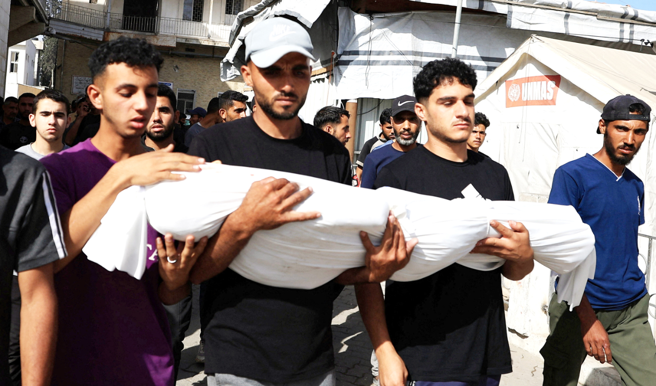 Mourners hold a body during Monday’s funeral of Palestinians killed in Israeli strikes at Gaza City’s Al-Ahli Arab Baptist Hospital. (Reuters)