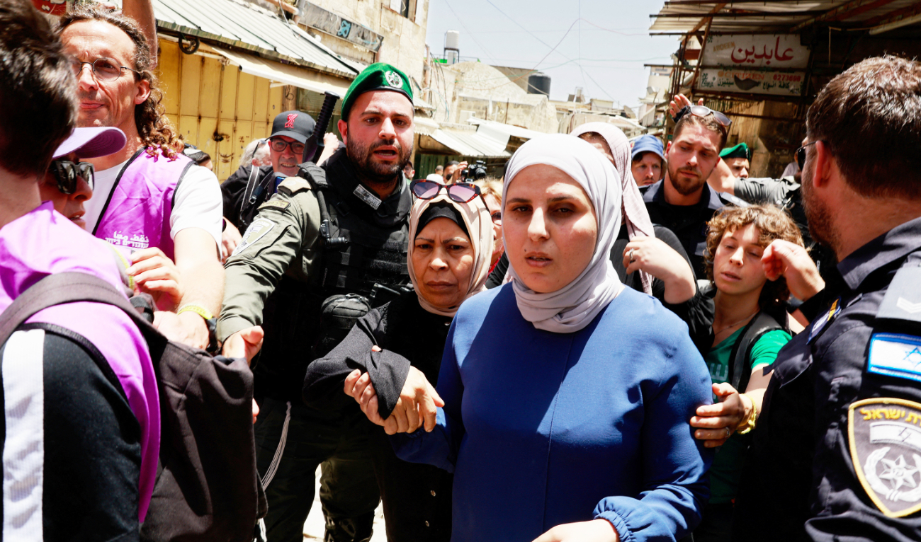 Palestinian women walk past Israeli police in Jerusalem’s Old City on Monday. (Reuters)