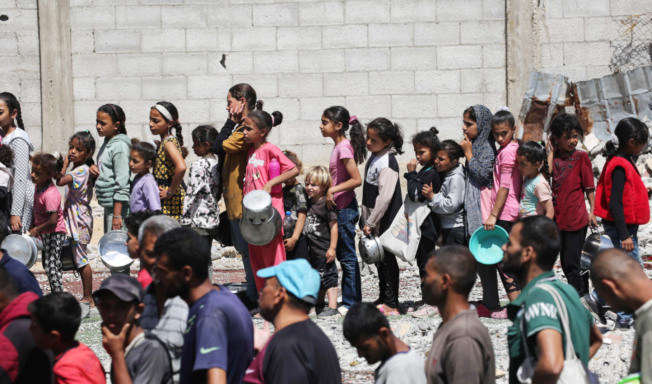 Palestinians gather to receive a hot meal at a food distribution point in the Nuseirat camp for refugees in the central Gaza Strip. (AFP)