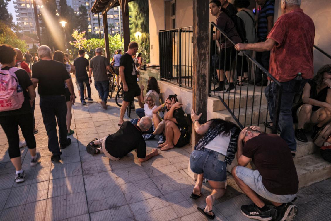People take cover as warning sirens sound of an incoming rocket attack in Tel Aviv on October 28, 2023. (File/AFP)