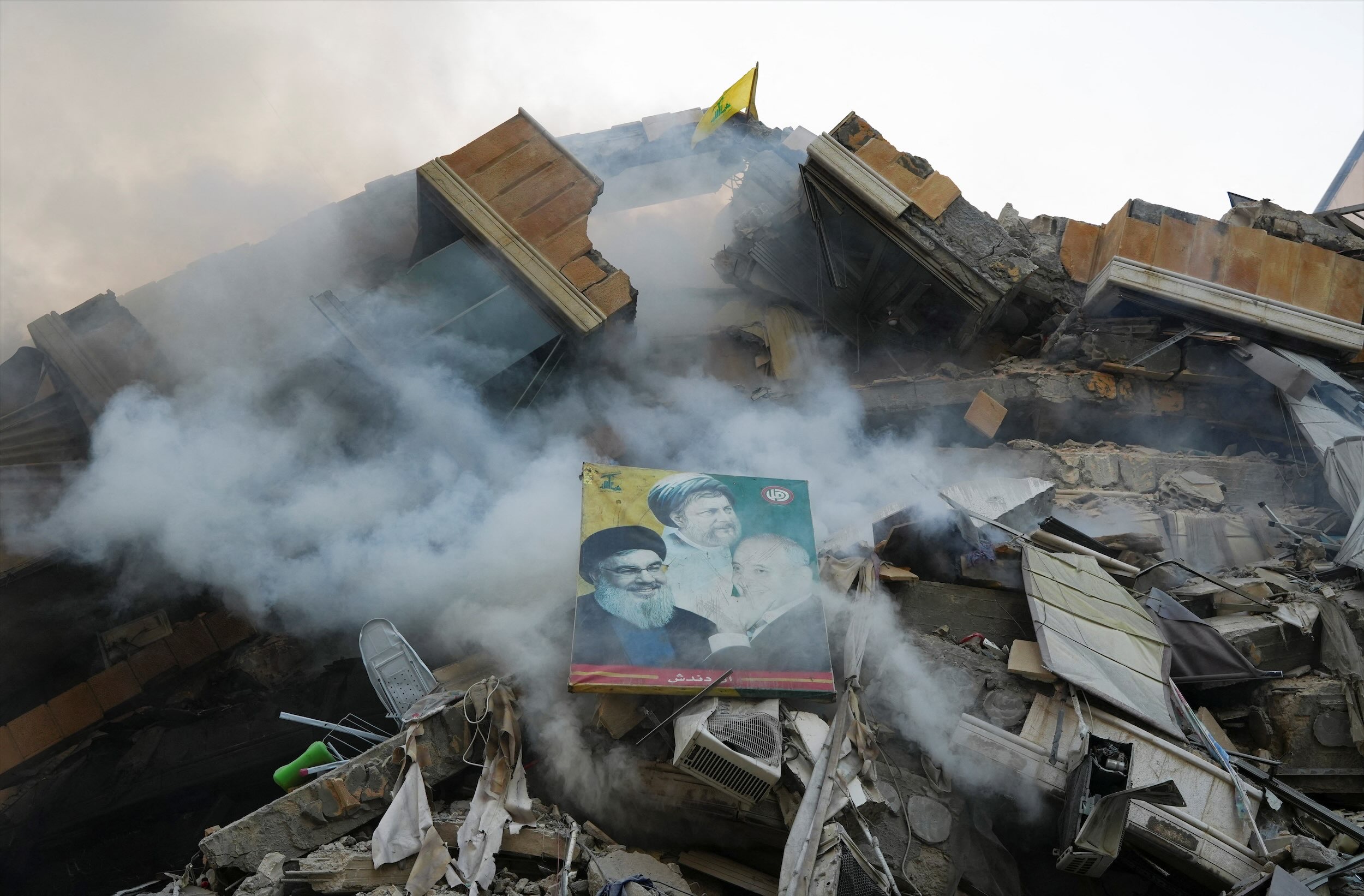 A poster depicting late Hezbollah leader Sayyed Hassan Nasrallah, Parliament Speaker Nabih Berri and the founder of the Shi'ite Amal movement Imam Musa al-Sadr, is placed on the rubble of damaged building. (Reuters)