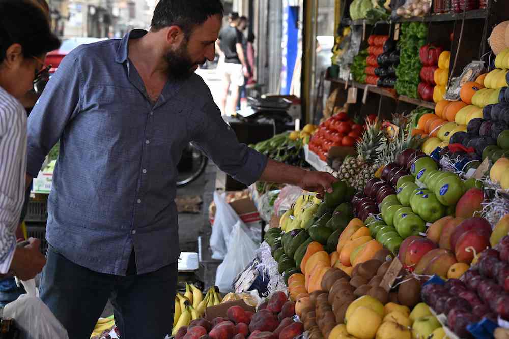 People shop for fruits at a stall, some of which were not available while deposed president Bashar Assad was in power, like kiwi, mango and pineapple, in the Shalaan Market in the Syrian capital Damascus. AFP